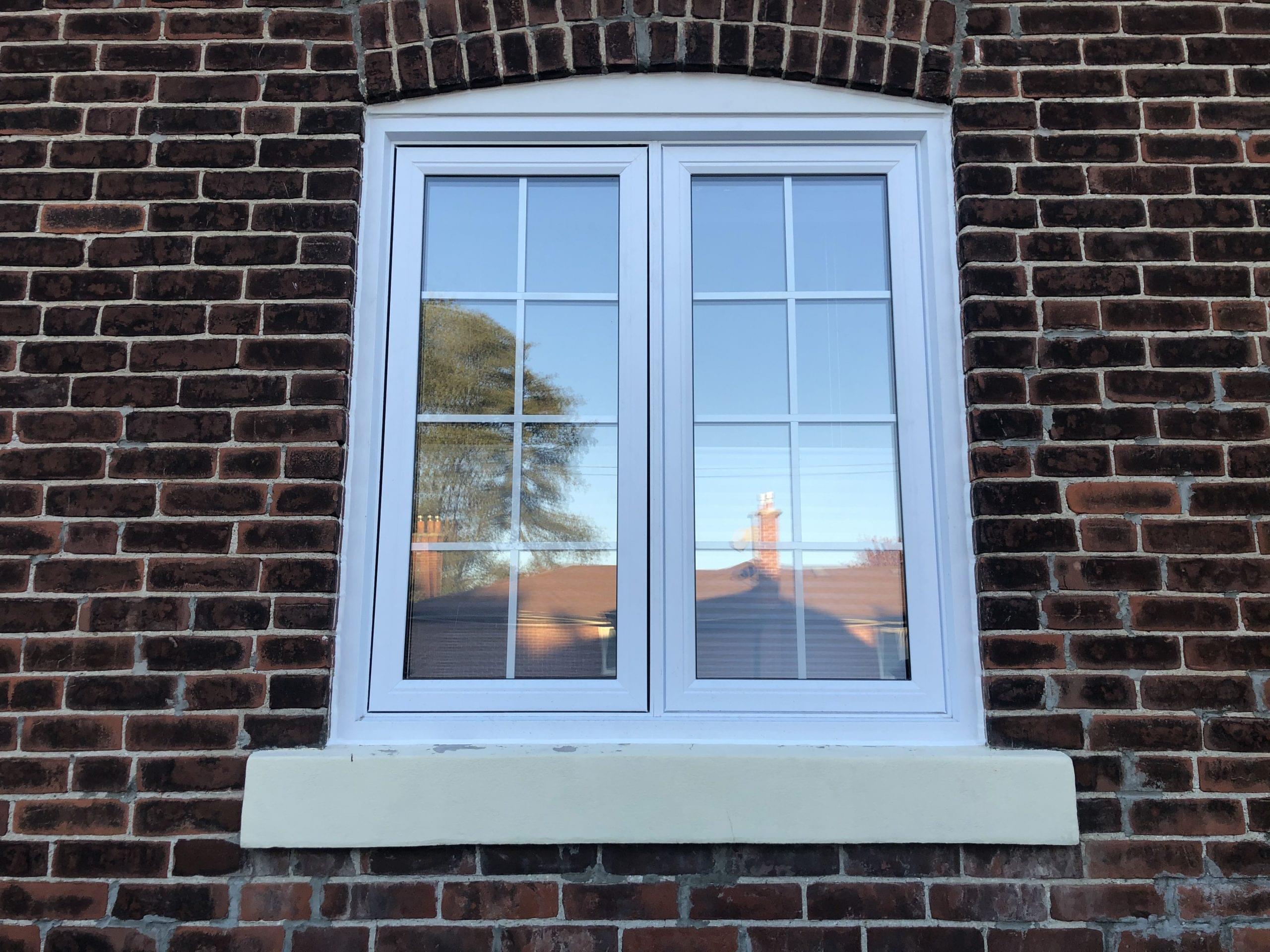 White vinyl window installed in insulated brick wall of a Toronto house.